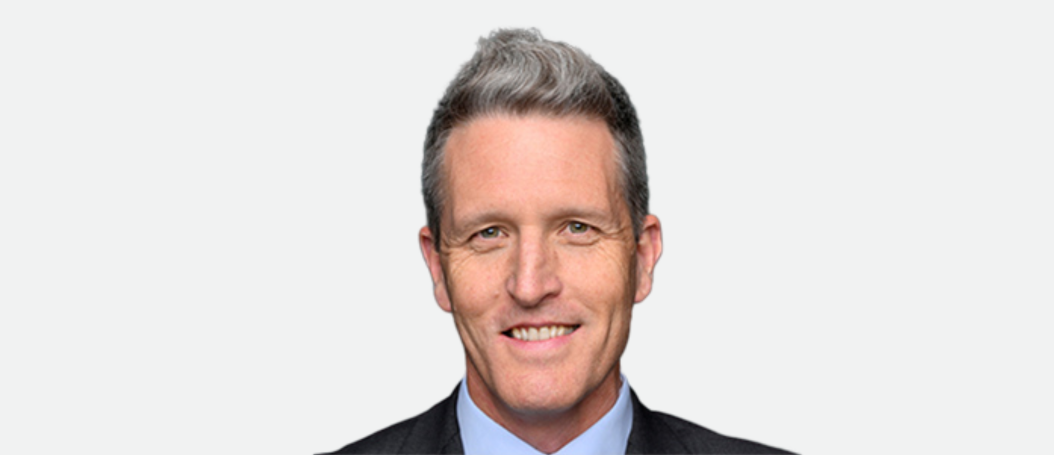Josh Wilson MP smiles to the camera. He is wearing a suit and collared business shirt.