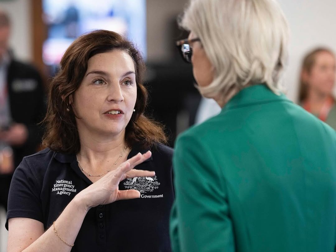 Close up shot of Jill explaining something, viewed over the shoulder of the Governor General.