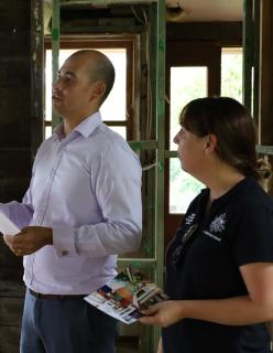 Two people stand in a gutted home. One is wearing a NEMA branded uniform.