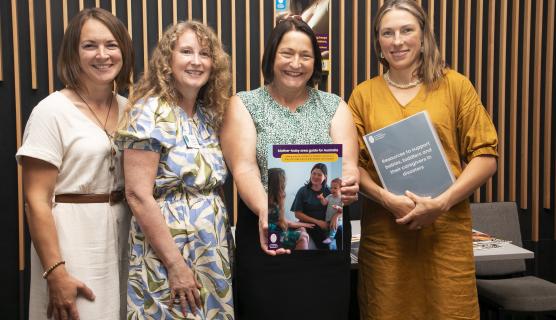 An image of four women holding a copy of the Community Protection for Infants and Young Children in Bushfire Emergencies Project