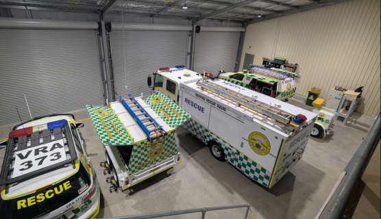 Photo from a high angle of the inside of the centre with emergency rescue cars and trucks and roller doors at the front.