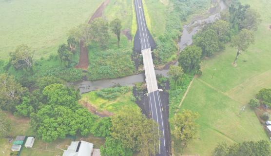 Aerial photo of the new raised Grieve Crossing Bridge on Gradys Creek Road in New South Wales. It shows a double-lane bridge surrounded by green fields.