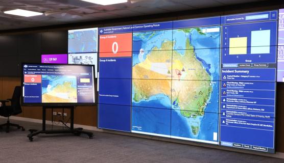 Photo in a room with many large floor-to-ceiling screens showing a map of Australia and list of active hazards.