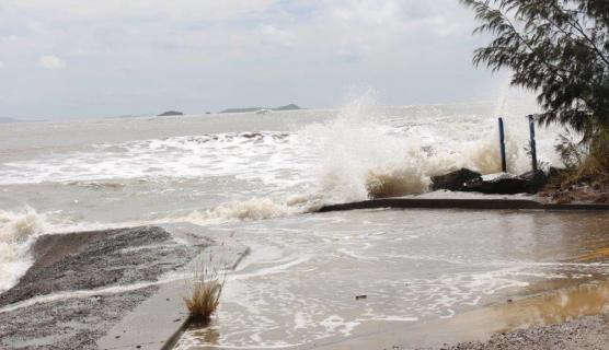 Photo of very rough ocean, grey/brown, hitting a coastal wall.