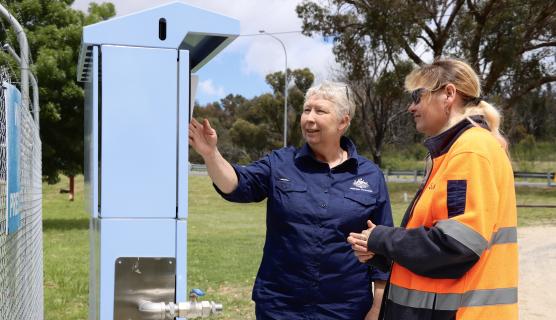Photo of Karen and another lady standing looking at a community notice board.