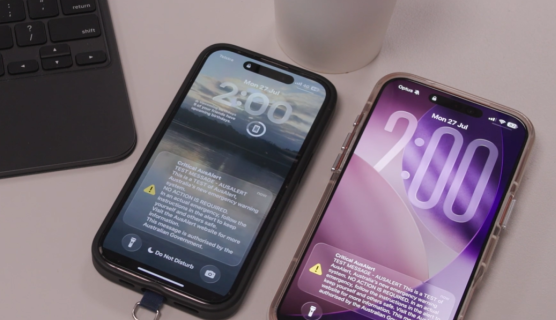 Photo of 2 smartphones on a desk, both showing 2pm and the AusAlert national test on screen.
