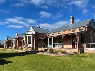 A brick house with a lawn under a blue sky.