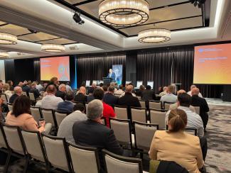 Photo of speaker on the stage speaking to audience 