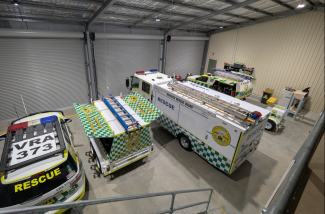 Photo from a high angle of the inside of the centre with emergency rescue cars and trucks and roller doors at the front.