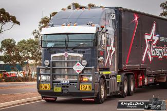 Front of a large transport truck with 'road train' signs on the bumper.