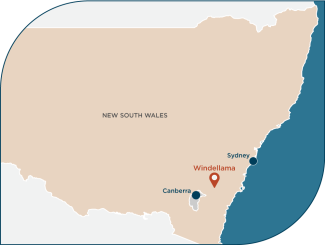 Stylised map of NSW and ACT with Canberra labelled in the southeast, Sydney on the coast, and an orange pin showing Windellama about halfway between.