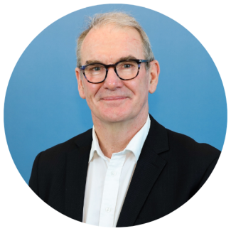 Headshot of Brendan with light blue background, cropped to a circle.