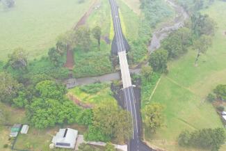 Aerial photo of the new raised Grieve Crossing Bridge on Gradys Creek Road in New South Wales. It shows a double-lane bridge surrounded by green fields.