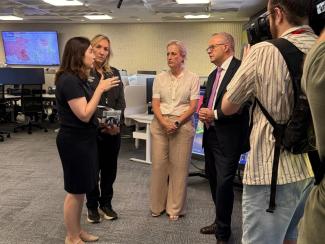 In the National Situation Room with cameraman in the foreground filming Jill and Katarina talking to Senator Katy Gallagher and Prime Minister Anthony Albanese. All look serious.