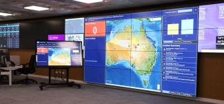 Photo in a room with many large floor-to-ceiling screens showing a map of Australia and list of active hazards.