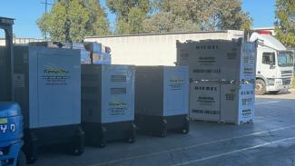 Photo of 3 large grey generators and 2 large tanks labelled diesel fuel.