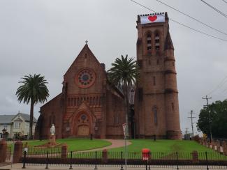 Photo of a church with a large red heart banner at the top of a turret.