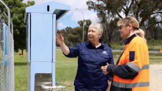 Photo of Karen and another lady standing looking at a community notice board.