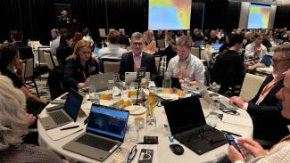 Photo of people sitting around a round table with laptops.